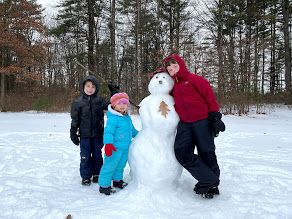 Three kids next to a snowman
