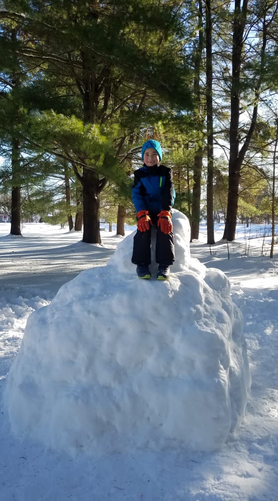 kid sitting on huge snowball