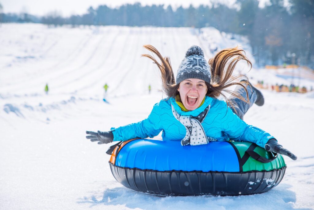 Woman Smiling in a tube sledding down a snowy hill