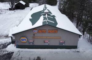 Upper view of Napa Auto Parts building; grey siding with green snowy roof